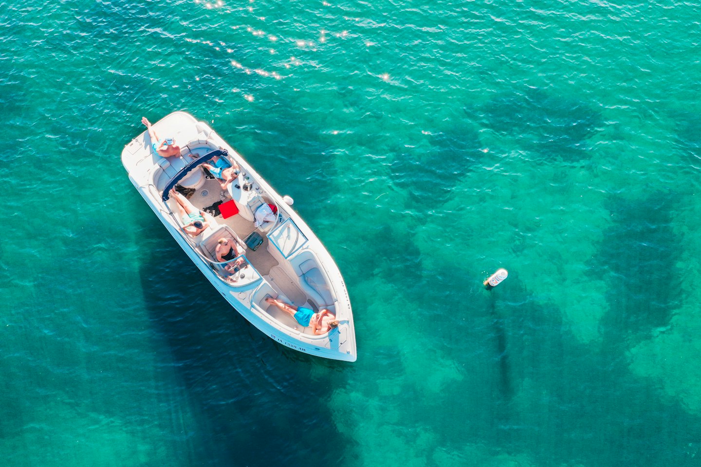People relaxing on a boat in clear turquoise water.