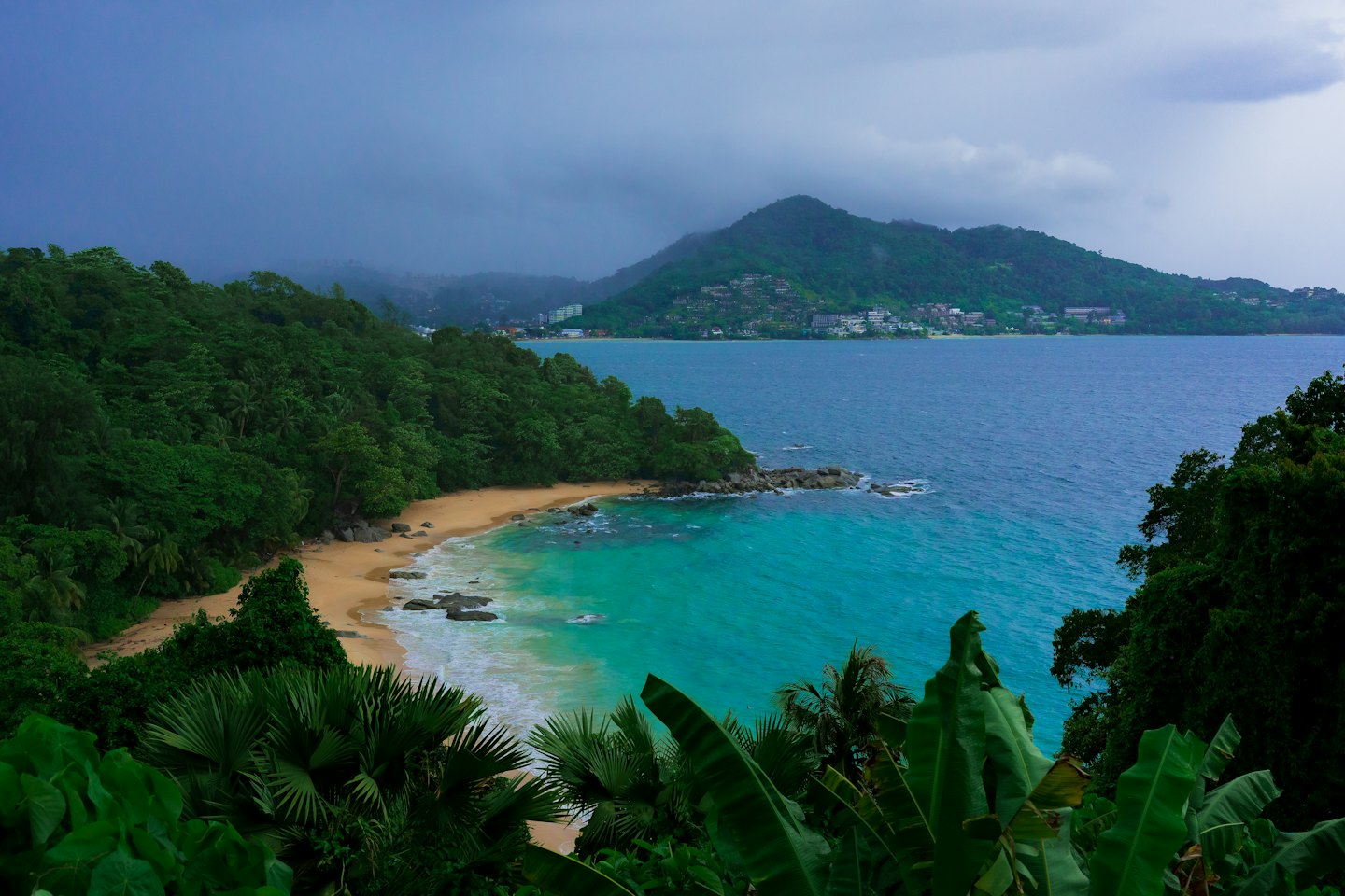 Lush jungle foliage borders a sandy beach on a tropical island.